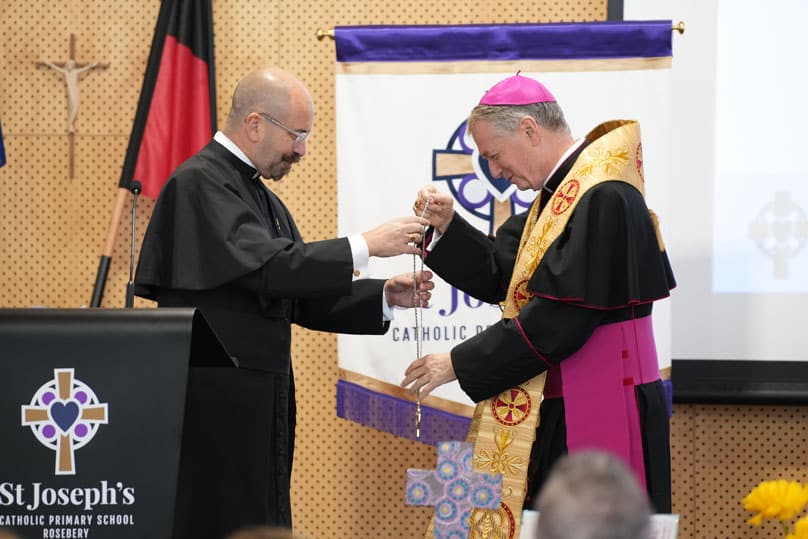 Fr Paul Smithers presenting Archbishop Anthony Fisher OP with a commemorative St Joseph’s School cross . Photo: Sydney Catholic Schools 
